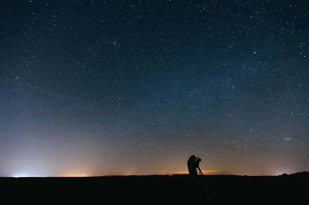 Astronomer adjusting a large telescope under the stars